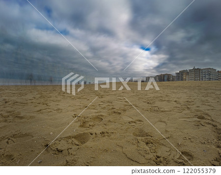 Dramatic Beach Scene with Reflections and Residential Buildings under Overcast Sky Dramatic Beach Scene with Reflections and Residential Buildings under Overcast Sky 122055379