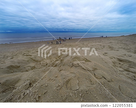 Expansive Sandy Beach with Overcast Skies and Distant Figures Relaxing Expansive Sandy Beach with Overcast Skies and Distant Figures Relaxing 122055381