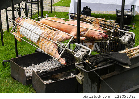 Roasting Pigs Over Open Charcoal Fires at an Outdoor Event Roasting Pigs Over Open Charcoal Fires at an Outdoor Event 122055382