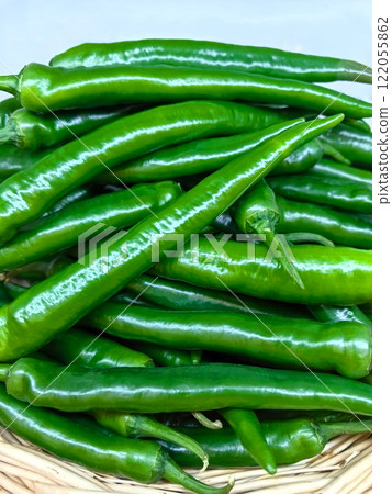 Fresh green peppers stacked high in a rustic basket at a local market stall Fresh green peppers stacked high in a rustic basket at a local market stall 122055862