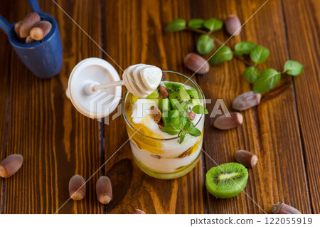 homemade yogurt with kiwi, honey and nuts in a glass on a wooden table 122055919