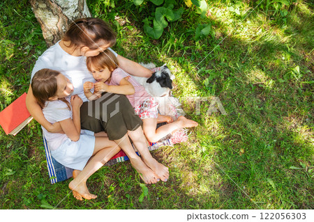 Family sharing a loving embrace under a tree on a sunny day 122056303