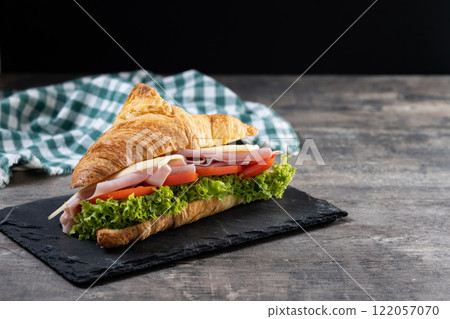 Croissant with ham, cheese and vegetables on wooden table 122057070