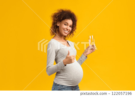 Healthcare concept. Pregnant lady with glass of water showing thumb up, pink background Healthcare concept. Pregnant lady with glass of water showing thumb up, pink background 122057196