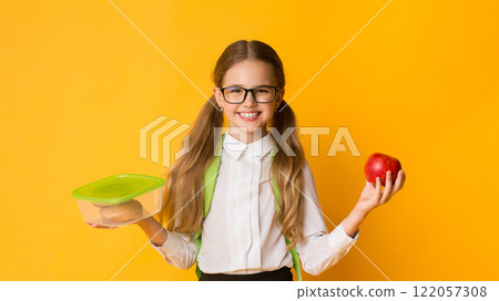 School Lunch. Happy Schoolgirl Holding Lunchbox With Sandwich And Apple Standing Over Yellow Background In Studio School Lunch. Happy Schoolgirl Holding Lunchbox With Sandwich And Apple Standing Over Yellow Background In Studio 122057308