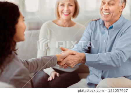 Gratitude. Close up of handshake of happy mature man and female doctor greeting each other at couple therapy session 122057437