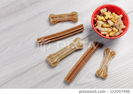 Dry pet food in a bowl and artificial dog chew bone food for dogs. 122057496