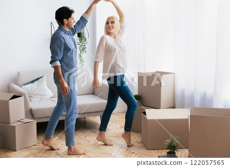 A couple dances in their new home, surrounded by moving boxes, celebrating their new beginning. 122057565