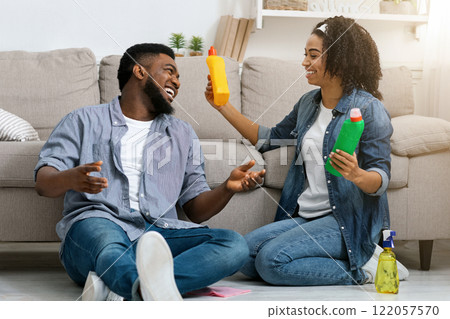 Young Black Couple Resting After Spring Cleaning Flat Together, Sitting On Floor And Laughing, Free Space Young Black Couple Resting After Spring Cleaning Flat Together, Sitting On Floor And Laughing, Free Space 122057570