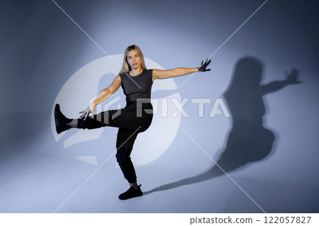Young dancer performing modern dance illuminated by spotlight in studio Young dancer performing modern dance illuminated by spotlight in studio 122057827