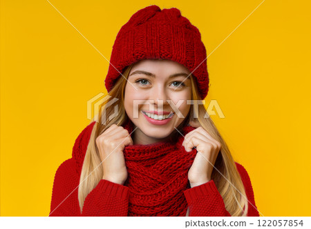Portrait of pretty smiling girl in blue knitted winter set over yellow background 122057854