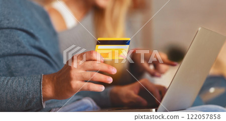 Unrecognizable Couple Using Laptop And Credit Card Shopping Online Ordering Something Sitting On Couch At Home. Selective Focus, Cropped Unrecognizable Couple Using Laptop And Credit Card Shopping Online Ordering Something Sitting On Couch At Home. Selective Focus, Cropped 122057858