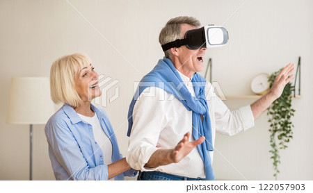 New feelings. Excited mature man using the VR glasses, wife standing behind husband 122057903