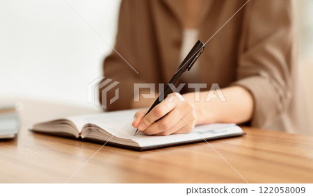 Personal Planner. Girl writing in notebook while sitting at working place, making notes, planning schedule, copyspace 122058009