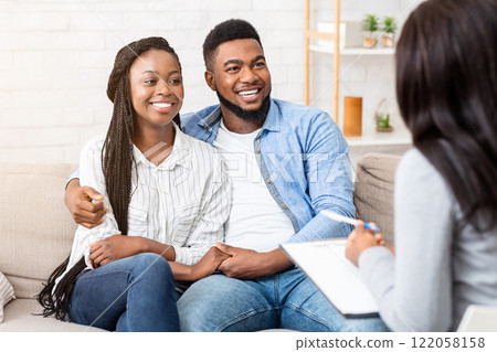 Happy black couple sitting in counselor's office after successful marital therapy, copy space Happy black couple sitting in counselor's office after successful marital therapy, copy space 122058158