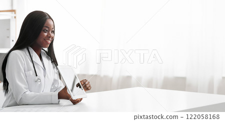 Young black lady doctor consultating patient, client looking at digital tablet screen, copy space 122058168