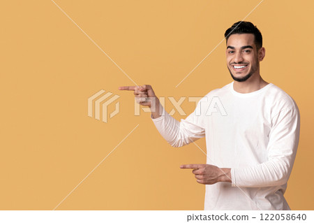 Best Offer. Cheerful Middle-Eastern Couple Pointing At Copy Space In The Middle, Joyful Young Arab Man And Woman Demonstrating Free Place For Your Advertisement On Yellow Background, Panorama 122058640