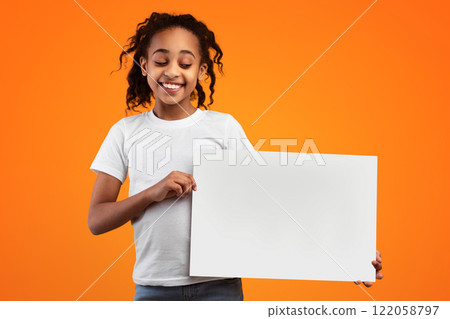 Banner For Advertising. Positive African American Girl Holding And Looking At Blank Square Paper Poster For Your Text And Smiling, Standing Isolated Over Yellow Studio Background, Free Copy Space Banner For Advertising. Positive African American Girl Holding And Looking At Blank Square Paper Poster For Your Text And Smiling, Standing Isolated Over Yellow Studio Background, Free Copy Space 122058797