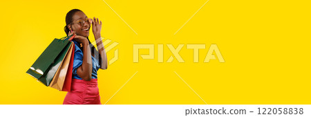 Pretty young black woman with colorful shopping bags posing over yellow studio background, panorama with copy space. Season sale concept Pretty young black woman with colorful shopping bags posing over yellow studio background, panorama with copy space. Season sale concept 122058838