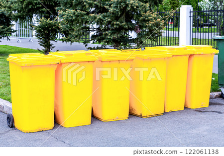 A row of new yellow waste containers at the city street. Modern garbage bins A row of new yellow waste containers at the city street. Modern garbage bins 122061138
