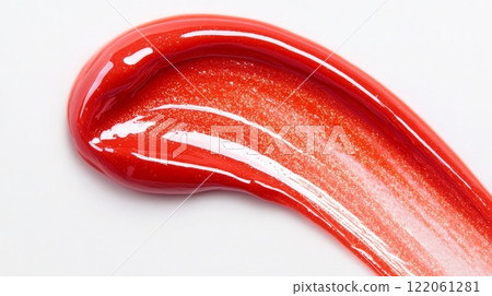 A thick, glistening stroke of vibrant red paint lies on a white surface, catching light and emphasizing its rich texture and shiny finish, suggesting a creative artistic application. 122061281