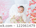 A cute girl baby in a red hakama who looks happy surrounded by spring cherry blossoms at the Hinamatsuri of the first festival 122061479