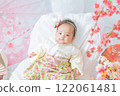 A cute girl baby in a red hakama who looks happy surrounded by spring cherry blossoms at the Hinamatsuri of the first festival 122061481