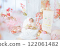 A cute girl baby in a red hakama who looks happy surrounded by spring cherry blossoms at the Hinamatsuri of the first festival 122061482