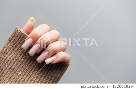 Woman showing stylish pink manicure with brown sleeve on grey background Woman showing stylish pink manicure with brown sleeve on grey background 122061929