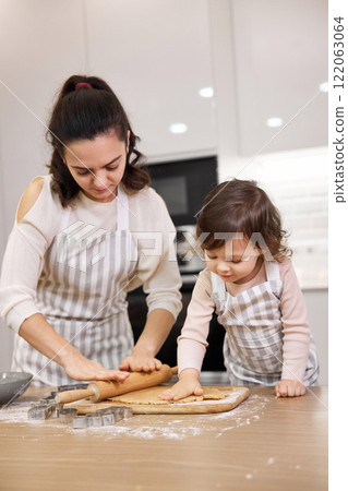 Happy mother and cute little child daughter using a rolling pin for homemade pastry. 122063064