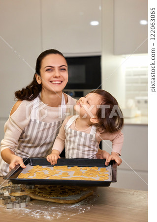 happy mother and little child daughter holding tray with gingerbread cookies in kitchen happy mother and little child daughter holding tray with gingerbread cookies in kitchen 122063065