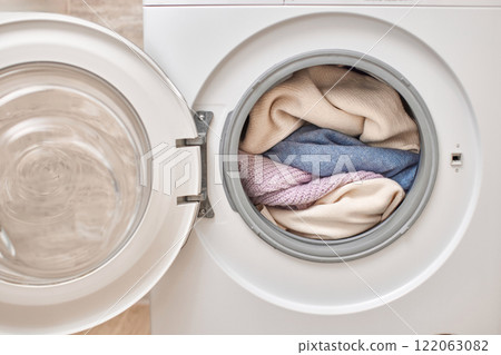Colorful and white laundry inside washing machine with open door. Close up. Colorful and white laundry inside washing machine with open door. Close up. 122063082