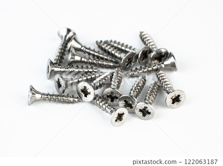 A collection of metal screws scattered on a white background. High quality photo 122063187