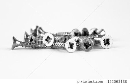 A collection of metal screws scattered on a white background. High quality photo 122063188