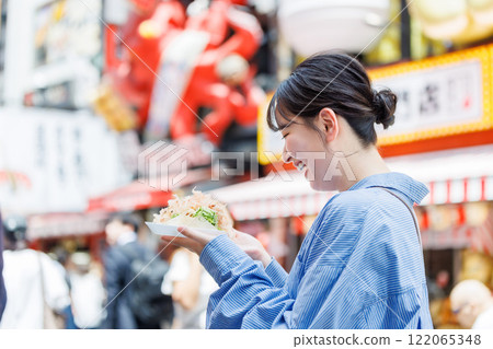 A woman eating the famous takoyaki in Dotonbori, Osaka 122065348