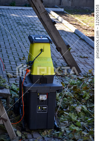 Autumn work in gardening, pruning and crushing branches, wood, in a shredder and mulcher 122065858
