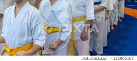 A close-up of a row of young athletes in white karate kimonos with clenched fists. A close-up of a row of young athletes in white karate kimonos with clenched fists. 122066162