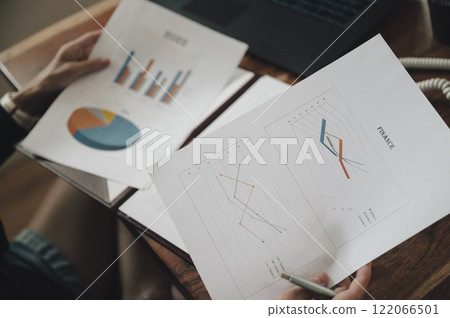 Over the shoulder view of a woman reviewing financial business documents with graphs and charts 122066501