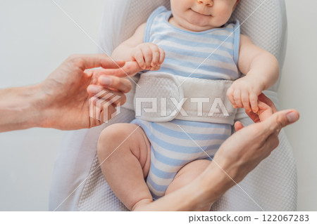 Adorable 3-month-old baby lying safely in a cozy infant cocoon secured with a special safety belt. Comfortable and protective design for newborn care. Parenting, safety, and baby comfort concept 122067283