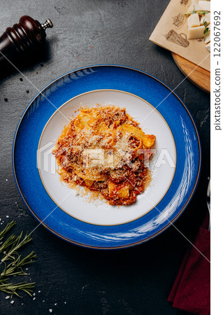 Traditional Italian bolognese pasta served in a stylish blue plate, topped with parmesan cheese Traditional Italian bolognese pasta served in a stylish blue plate, topped with parmesan cheese 122067692