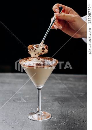 Indulgent creamy dessert spooned from a martini glass, dusted with rich cocoa powder 122067704