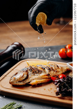 Squeezing lemon juice over grilled fish for perfect flavor enhancement 122067710