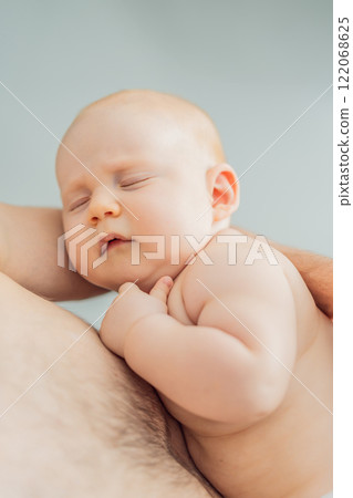 A baby peacefully falls asleep in his father's arms, skin-to-skin. A heartwarming and intimate moment of love, bonding, and parenthood, showcasing the deep connection between father and child A baby peacefully falls asleep in his father's arms, skin-to-skin. A heartwarming and intimate moment of love, bonding, and parenthood, showcasing the deep connection between father and child 122068625