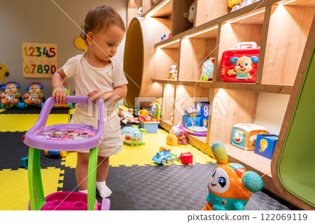 Child exploring playroom with engaging toys and bright design. Concept of fun and educational play indoors 122069119