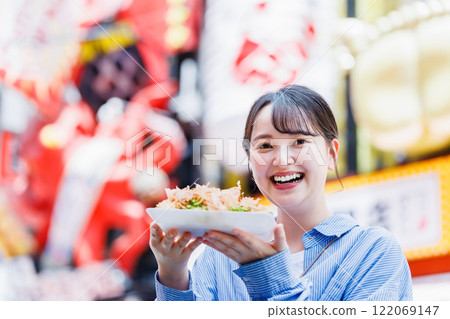 一位女士在大阪道頓堀吃著名的章魚燒 122069147