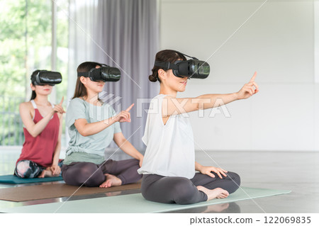 A woman doing yoga with VR goggles (yoga class) 122069835