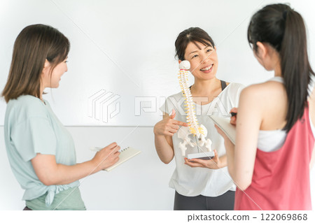 Yoga instructor teacher and women explaining while looking at pelvis, coccyx, skeleton sample (study session / class) Yoga instructor teacher and women explaining while looking at pelvis, coccyx, skeleton sample (study session / class) 122069868