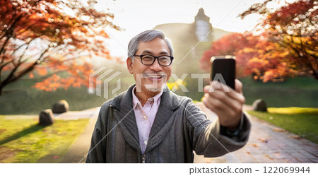 一名老人在公園使用智慧型手機進行視訊通話。 一名老人在公園使用智慧型手機進行視訊通話。 122069944
