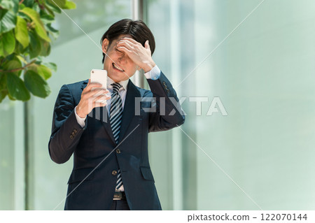 A young Asian male businessman in a suit operating a smartphone (investment trusts, NISA, new NISA, stocks) A young Asian male businessman in a suit operating a smartphone (investment trusts, NISA, new NISA, stocks) 122070144