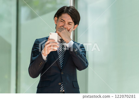 Asian male businessman looking at smartphone in office (shock, sad, sympathy, misery, worry, trouble) Asian male businessman looking at smartphone in office (shock, sad, sympathy, misery, worry, trouble) 122070281